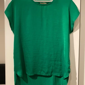 Grön topp från Holly & Whyte - Snygg grön topp från Holly & Whyte by Lindex. Den har en enkel design med korta ärmar och rund halsringning. Perfekt för en avslappnad stil.