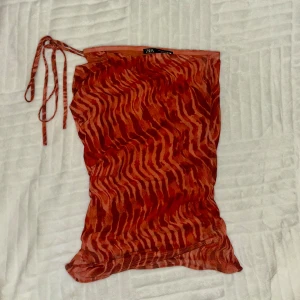 Zara orange topp - Säljer en supersnygg orange topp från Zara, med skitsnyggt mönster i mesh. Det finns två snören så man kan styla toppen på flera olika sätt, den är perfekt för fest och är i storlek S. Mycket bra skick då den nästan aldrig blivit använd. Säljer för att den inte kommer till användning. 