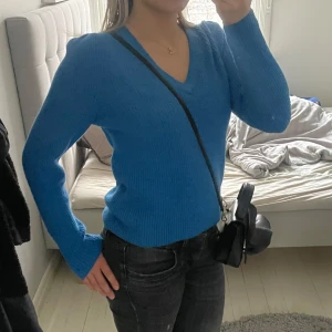 Blå ribbad tröja med v-ringning - Säljer en snygg blå ribbad tröja med v-ringning. Tröjan har långa ärmar och en skön passform som passar perfekt till vardags. Perfekt för att hålla sig varm och stilren under kyligare dagar.