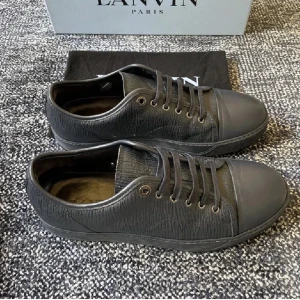Svarta sneakers från Lanvin - Snygga svarta sneakers från Lanvin med snörning och en stilren design. Skorna har en texturerad yta och en tåhätta i samma färg. Perfekta för en stilren look.
