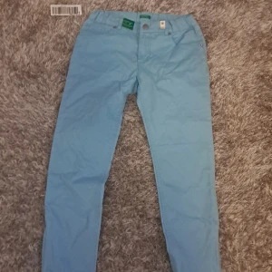 Ljusblå byxor från United Colors of Benetton - Notera att det inte är vuxenstorlek! Snygga ljusblå capri jeans från United Colors of Benetton med justerbar midja. Perfekta för en avslappnad stil. Byxorna har en klassisk design med fickor bak och fram.