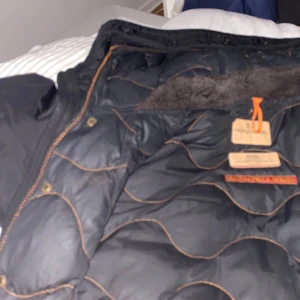 Svart jacka från Parajumpers - Säljer en svart jacka från Parajumpers med huva och snygga detaljer. Jackan har en quiltad insida och dragkedja framtill sönder me enkelt att fixa. Perfekt för kyligare dagar. Päls finns 