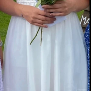 Vit spetsklänning - Charmig vit klänning med spetsdetaljer och knappar på baksidan med en kjol av tyll. Använd en gång.