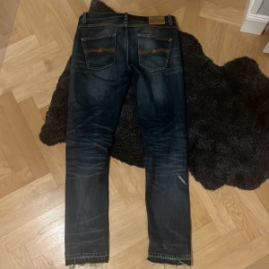 Mörkblå jeans från Nudie Jeans - Snygga mörkblå jeans från Nudie Jeans med as sköna slitningar och tvätt. Dem är i modellen lean dean. Priset kan vara diskuterbart!