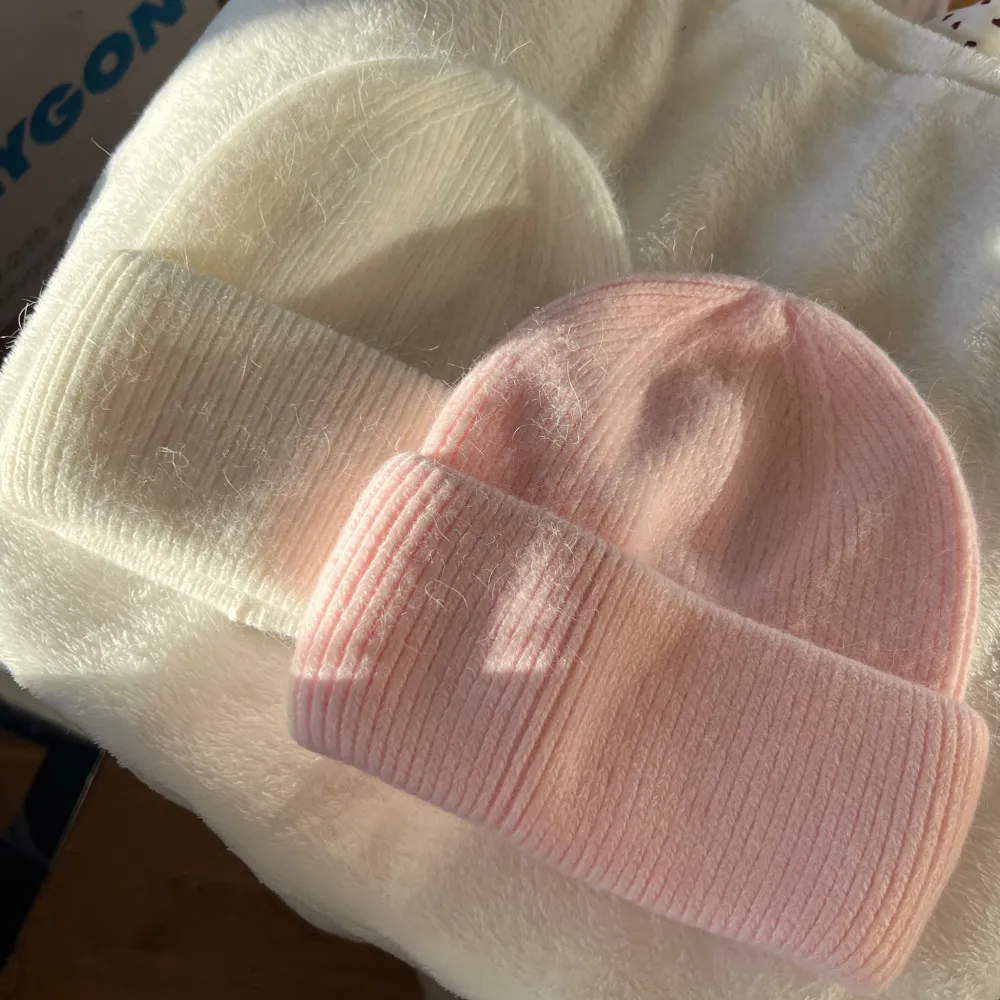 Två mysiga stickade mössor i rosa och vit färg. De har en ribbad design och är perfekta för kyliga dagar. Mössorna är mjuka och bekväma, vilket gör dem till ett stilrent val för vintern. 200kr/st . Asusteet.