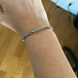 Silverfärgat armband - Snyggt silverfärgat armband med tvinnad design. Perfekt för att ge en elegant touch till din stil. Armbandet är enkelt och stilrent, vilket gör det lätt att matcha med andra smycken. Den är 20 cm lång 