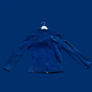 Nike tech fleece - Säljer en blå Nike Tech Fleece som bara ligger hemma och samlar damm. Den är i toppskick, knappt använd och fortfarande lika fräsch som när den köptes. Mjuk, bekväm och perfekt för både träning och vardagsbruk.  Storlek: xl junior Färg: Blå Skick: 9,5/10 – som ny, inga fläckar eller slitage               pris kan diskuteras 