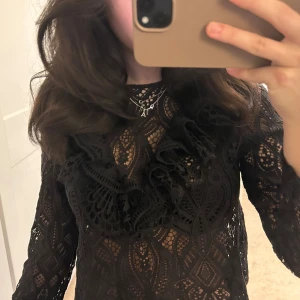 Topp - Elegant svart spetsblus med långa ärmar och volangdetaljer. Perfekt för en stilfull look. Skriv för frågor ❤️