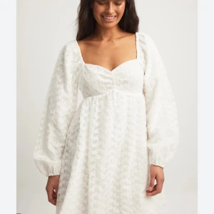 Vit klänning med puffärmar - Charmig vit klänning med långa puffärmar och en söt hjärtformad urringning. Klänningen har en lätt struktur i tyget som ger en elegant touch. Perfekt för studenten. Säljer den pågrund av fel storlek. Den är aldrig använd och prislapp sitter kvar🌼