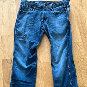 Blå replay anbass jeans - Snygga blå jeans från Replay med en klassisk femficksdesign. De har en knappgylf och är tillverkade i ett stretchigt material för extra komfort. Perfekta för en avslappnad stil.