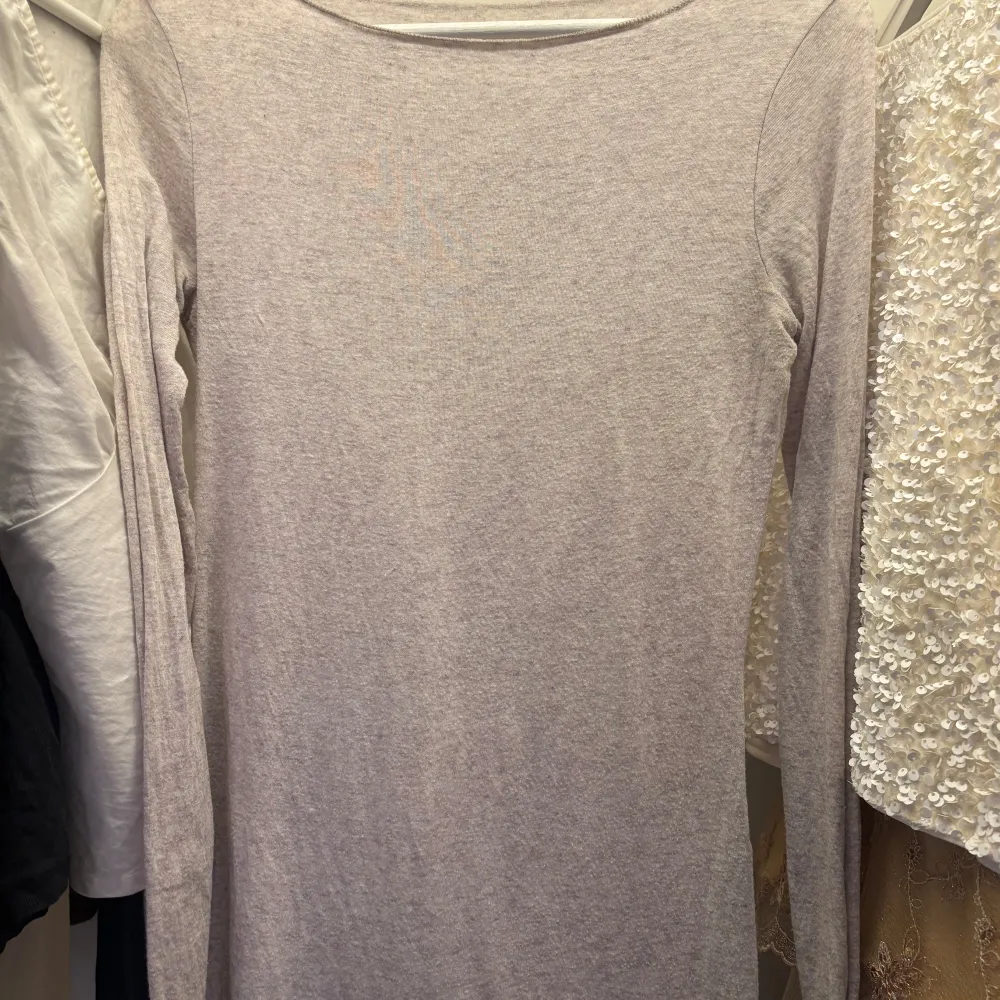 Säljer en stilren beige långärmad tröja. Perfekt för en enkel och avslappnad look. Tröjan har en rund hals och är gjord i ett mjukt material. Ny pris 570kr. Neuletakit & Villapaidat.