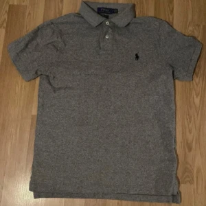Grå pikétröja från Ralph Lauren - Säljer en stilren grå pikétröja från Ralph Lauren i custom slim fit. Tröjan har korta ärmar och en klassisk krage med knappar. Den ikoniska loggan är broderad på bröstet. Perfekt för en avslappnad men ändå snygg look. Den är i storlek M men passar i S också, tveka inte med att fråga frågor om denna Piketröjan. Pris går att diskuteras✅