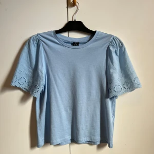 Ljusblå topp från Vero Moda - Säljer en söt ljusblå topp från Vero Moda med korta ärmar och fina spetsdetaljer. Endast använd 1 gång. Skriv för fler bilder eller funderingar💕