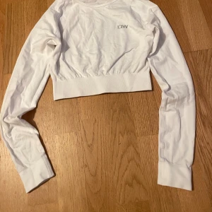 Vit långärmad croppad tröja från ICANIWILL - Säljer en vit långärmad croppad tröja från ICANIWILL. Perfekt för träning eller en avslappnad dag. Tröjan har en elastisk midja och är tillverkad i ett mjukt material för extra komfort. Använd fåtal gånger. 