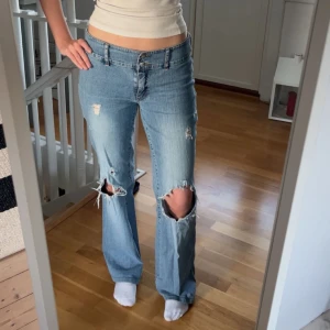 Blå jeans med slitningar - Snygga blå utsvängda jeans med slitningar. Säljer dom då de inte längre kommer till någon användning 💕passar perfekt på mig som är ca 160cm lång 💞gjort slitningarna själv!