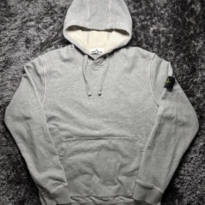 Grå hoodie från Stone Island - Säljer en stilren grå hoodie från Stone Island med klassisk logga på ärmen. | helt ny hoddie värd 3000| storlek XL men sitter bra som L. Skick 9/10| funderingar kontakta mig. 