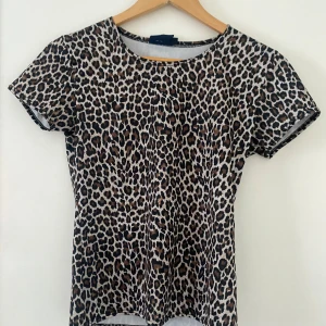 Leopardmönstrad topp från Mari Philippe - Snygg leopardmönstrad topp från Mari Philippe i storlek M. Den har korta ärmar och en rund halsringning. Perfekt för att ge din outfit en djärv touch.