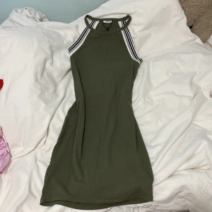 Olivgrön ribbad klänning från Noisy May - Snygg olivgrön klänning från Noisy May med ribbad textur och sportiga ränder vid axlarna. Klänningen har en tight passform och är ärmlös, perfekt för en stilren look. Den är både bekväm och trendig, idealisk för olika tillfällen. Skriv vid frågor💕
