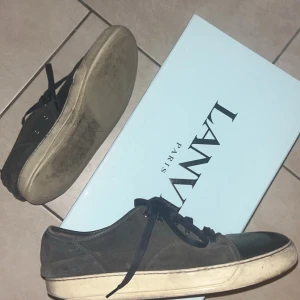 Svarta sneakers från Lanvin - Snygga svarta sneakers från Lanvin med snörning och en stilren design. Skorna är i ett bra skede och box tillkommer. Men har ett litet håll i sulan
