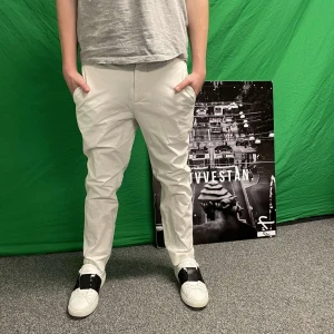 Vita chinos - Snygga vita chinos med normal passform och midwaist. Perfekta för en stilren look. De har fickor fram och bak, vilket ger en praktisk touch.