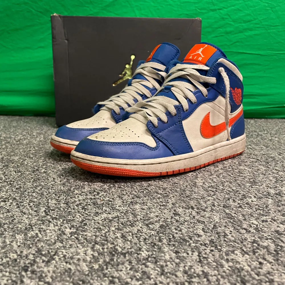 Snygga Nike Air Jordans i en fräsch kombination av blått, orange och vitt. Skorna har klassisk snörning och en iögonfallande orange sula. Perfekta för dig som vill sticka ut med stil.. Kengät.