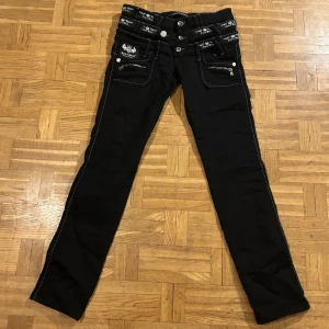 Svarta jeans med detaljer från Cipo & Baxx - Snygga lågmidjade svarta jeans från Cipo & Baxx med vita sömmar och flera dragkedjor. Sjukt snygga byxor med tre ”midjor”. Jätte bekväma och fina, säljer då de tyvärr är lite för korta på mig.   Mått: 37cm rakt över midjan, 76cm innerbenslängd, 93cm full längd, 20cm grenhöjd. Det är bara fråga ifall du undrar över något.💗💗