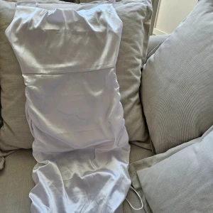 Vit Spaghetti glansig klänning - En elegant vit klänning med smala axelband och en åtsittande passform. Klänningen har en rynkad detalj på sidorna, och kan vara väldigt kort eller midi. Den är ganska glansigt.  Har också dragkedjan på vänster sida( 42 cm), så praktiskt och lätt att ta på / ta av sig.  Jättebra sikt men det finns liten slitning på baksidan, som inte märks, bara när man noggrant inspektera tyget. Kolla den sista bilden( 3 cm) , har zoomat för att det ska synas.