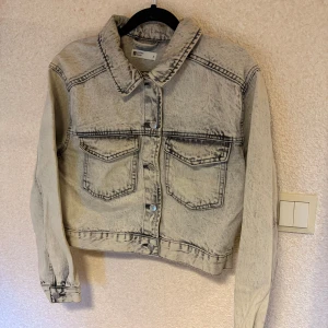 Grå jeansjacka från Perfect Jeans - Säljer en cool grå jeansjacka från Perfect Jeans. Jackan har en klassisk krage, knappar framtill och två bröstfickor med lock. Den har en avslappnad passform och långa ärmar med knapp vid ärmslut. Perfekt för en casual look!
