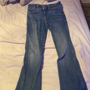 Blå bootcut jeans - Snygga blå bootcut jeans med hög midja och dubbla knappar. Perfekta för en avslappnad stil. Klassisk design med fickor fram och bak.