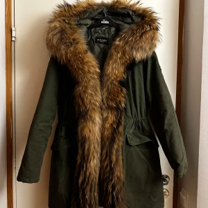 Grön parkajacka med pälsdetaljer från Hollies - Säljer en snygg grön parkajacka från Hollies med stor, fluffig äkta päls. Bra skick. Storlek S