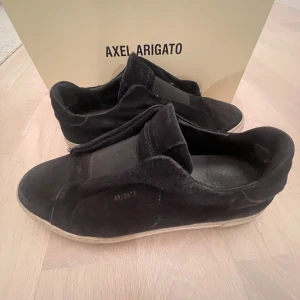 Arigato skor  - Säljer nu dessa axel arigato skor pågrund av att de dels blivit för små men även att jag har tröttnat på dem. Ägt de i ca 2 år och kommit mycket till användning. Därav har de att par skavanker såsom att mockan är lite ljusare och har några märken, hälen på skon har även hål i sig. Dem är i storlek 42. En arigato kartong medföljs också.