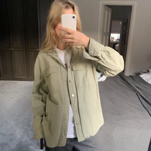 Olivgrön overshirt - Säljer en snygg olivgrön overshirt i bra skick. Den har en avslappnad passform med långa ärmar och knappar framtill. Perfekt för lager-på-lager under hösten eller våren. Passar både till vardags och lite mer uppklädda tillfällen. Storlek xs men passar större stl då den är lite oversized