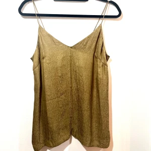 Linne med tunna axelband - Säljer ett stilrent  linne med tunna axelband.  Materialet är mjukt och bekvämt, vilket gör det idealiskt för både vardag och fest. 