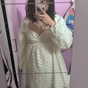 NA-KD klänning vit - Säljer en superfin vit klänning i storlek 38. Den har ett blommigt mönster och långa ärmar, perfekt för studenten, Klänningen är i nytt skick och har en söt, romantisk stil. Ta gärna kontakt vid frågor 