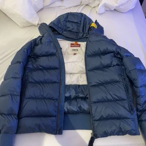 Blå dunjacka från Parajumpers - Säljer en snygg blå dunjacka från Parajumpers i mycket bra skick. Jackan har en quiltad design med dragkedja och huva, perfekt för kyliga dagar. Storlek L 