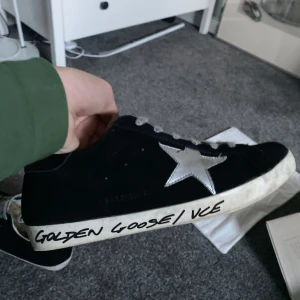 Svarta sneakers från Golden Goose - Säljer ett par svarta Golden Goose sneakers med den ikoniska silverstjärnan på sidan dem är i storlek 40 och orginalförpackning ingår samt broschyrer och en dustbag 