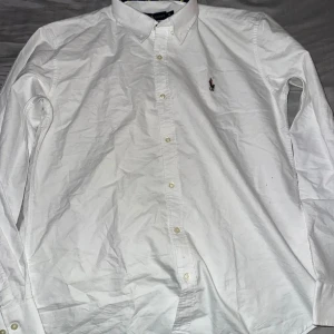 Vit skjorta från Ralph Lauren - Säljer en klassisk vit skjorta från Ralph Lauren i bomull. Skjortan har långa ärmar och en broderad logga på bröstet. Perfekt för både vardag och fest! 🕺