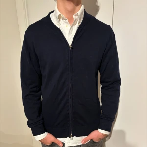 Mörkblå kofta från Grand Frank S - Blå  kofta från märket Grand Frank , storlek S. Bra använt skick, inga defekter men lite urtvättad, inget som syns.Modell på bild är 182/67kg. Hör av dig vid eventuella frågor! Mvh CAVI