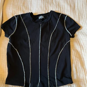 Svart t-shirt från Diesel - Säljer en svart t-shirt från Diesel i mycket bra skick. Den har vita kontrastsömmar som ger en cool look. Perfekt för vardagsbruk eller en avslappnad utekväll. Passar bra till jeans med stövlar eller sneakers!