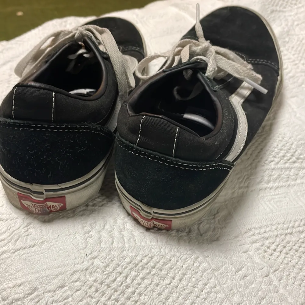 Säljer ett par klassiska svarta Vans sneakers i använt helt okej skick. Blir fina med nya skosnören öva lite rengöring. De har en vit sula och vita snören, med den ikoniska vita sidostripen. Insidan och sulan är i bra skick. Perfekta för vardagsbruk och ger en skön streetstyle-look. Passar till det mesta och är superbekväma!               . Skor.