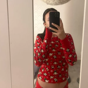 Röd jultröja med pingvinmönster - Superfin röd jultröja med gulligt pingvinmönster över hela. Perfekt för att mysa i under julen! Tröjan är långärmad och har en normal passform. Den kommer även med ett par matchande tights.🎄