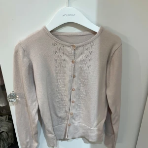 Ljusrosa kofta  - Säljer en superfin ljusrosa kofta. Den har ett snyggt stickat mönster framtill och knäpps med små knappar. Perfekt för både vår och höst, och den är i mycket bra skick. Passar perfekt till både jeans och kjol!