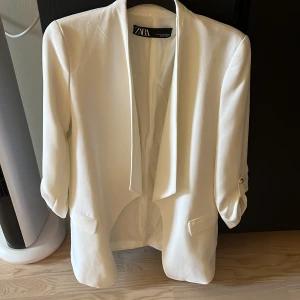 Vit kavaj från Zara - Säljer en stilren vit kavaj från Zara i mycket bra skick. Den har en elegant design med långa ärmar och en klassisk passform. Perfekt för både fest och formella tillfällen. Kavajen är i storlek xs och har en tidlös look som passar till det mesta. 🕊️