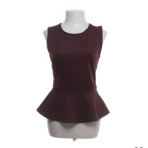 Vinröd topp från ONLY - Snygg vinröd topp från ONLY i storlek M. Den är ärmlös och baksidan har ett vackert spetsmönster och en liten knappdetalj vid nacken. 