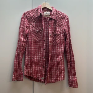 Röd rutig skjorta från Ralph Lauren - Säljer en snygg röd rutig skjorta från Ralph Lauren. Skjortan har långa ärmar och knappar framtill. Perfekt för en avslappnad stil eller en cowboy-look. Den är i bra skick! Den är lite liten i storleken och passar snarare XS