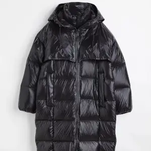 H&M Premium Selection En oversized, vadlång kappa i quiltad, vävd kvalitet med fyllning av 80 % dun och 20 % fjäder. Kappan har ståkrage, huva med dragsko och löst ok med tvåvägsdragkedja fram. Dragkedja fram, passpoalerade sidfickor och lätt nedhasad axel. Lång ärm med resår vid ärmslut. Rakt skuren nederkant och sprund i sidorna med dragkedja. Fodrad.  Art.nr:1106519002