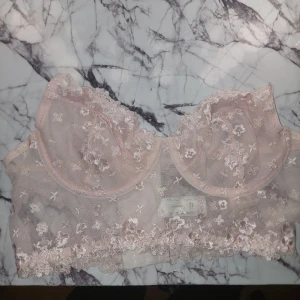 Rosa spets-bh från Reserved - Säljer en superfin rosa spets-bh från Reserved. Den har ett vackert blommönster och justerbara axelband. Perfekt för att känna sig extra lyxig till vardags eller vid speciella tillfällen. 💖