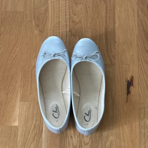 Silver ballerinaskor med rosett - Säljer ett par söta silver ballerinaskor från Clou i storlek 37. De har en fin liten rosett på ovansidan och är perfekta för vår och sommar. Skorna är i bra skick och passar både till vardags och festliga tillfällen.