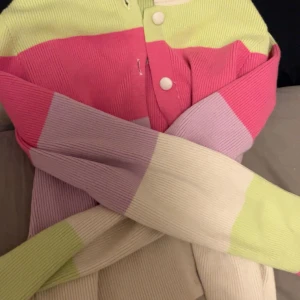 Färgglad randig kofta - Säljer en superfin kofta med breda ränder i rosa, lila, beige och limegrön. Den är ribbad och har knappar framtill. Perfekt för att liva upp garderoben! 🧥