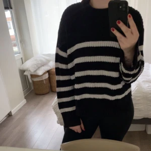 Svart och vit randig stickad tröja - Mysig och stilren svart och vit randig stickad tröja. Perfekt för kyliga dagar med sin bekväma passform och långa ärmar. Passar både till vardags och lite finare tillfällen. Ett måste i garderoben för höst och vinter!